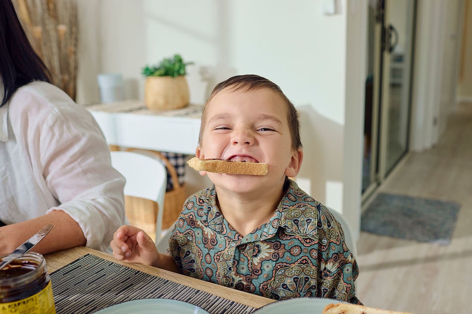 Small boy eating vegemite toast at the table